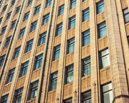 Un palazzo di rivestimento chiaro visto dal basso, con file di finestre
