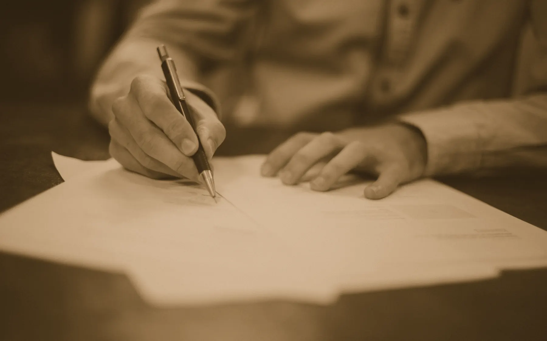 La mano di un professionista che firma un documento sulla scrivania