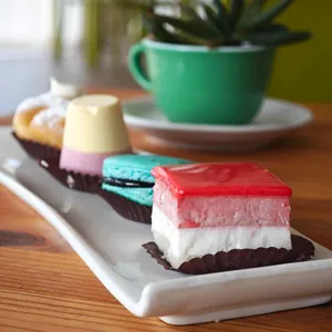 Pasticcini su un vassoio: una bavarese ai frutti di bosco, un macaron e un dolce con la gelatina rossa