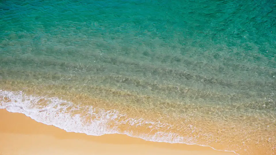 Il mare turchese che arriva sulla sabbia, visto dall'alto