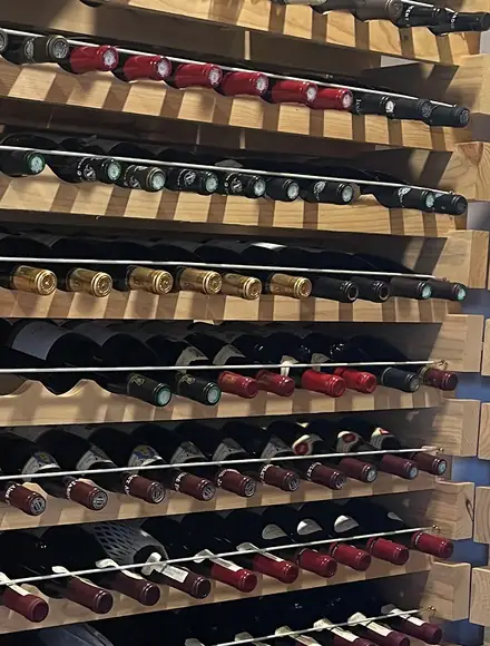 Bottiglie di vino coricate nelle rastrelliere di legno di una cantina