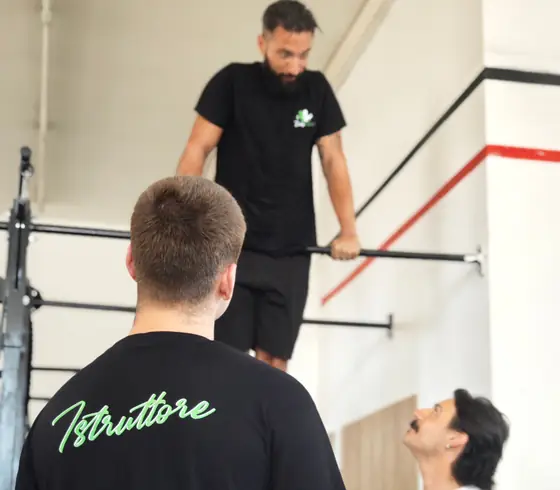 Un allievo alle parallele, seguito da due istruttori