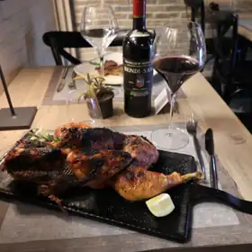Pollo alla brace servito su un tagliere, con un calice di vino rosso