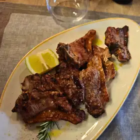 Carne alla brace con limone e rosmarino, su un piatto ovale