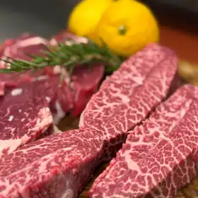 Tagli di manzo marezzati su un tagliere, con rosmarino e limoni