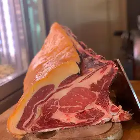 Un grande taglio di manzo frollato su un tagliere, davanti alla cella