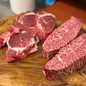 Bistecche marezzate su un tagliere di legno d'ulivo