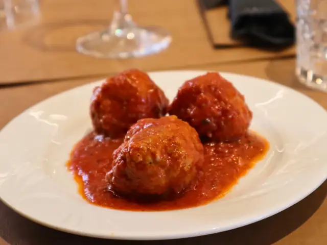 Tre polpette al sugo in un piatto bianco