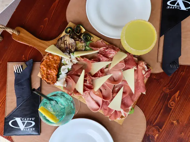 Il tagliere dell’aperitivo visto dall’alto: salumi, formaggio, verdure grigliate e due drink