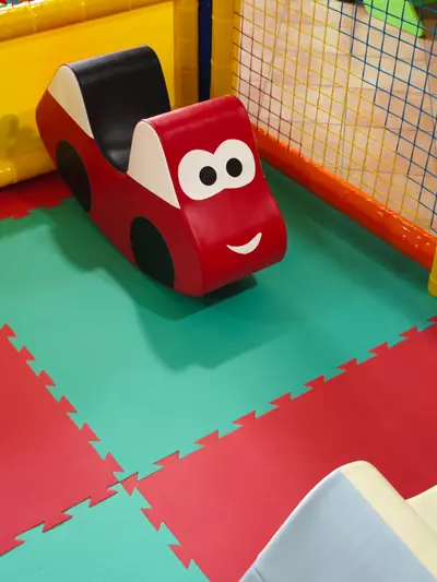 Una macchinina imbottita che sorride, sui tappeti colorati