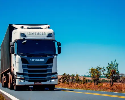 Un camion bianco con il rimorchio su una strada di campagna, sotto il cielo azzurro