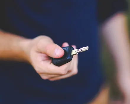 Una mano porge una chiave d'auto