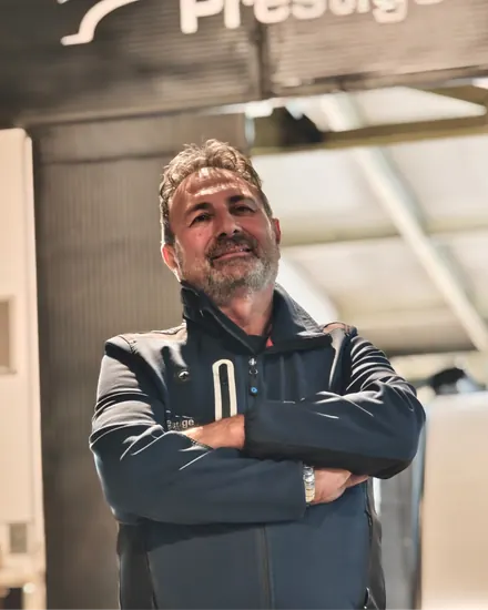 Il titolare della carrozzeria a braccia conserte, sotto l'insegna Prestige dell'officina