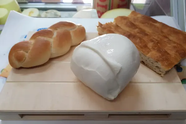 Una mozzarella accanto a un pane intrecciato e a una focaccia