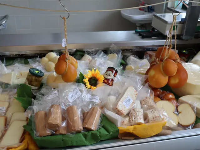 Il banco dei formaggi: scamorze e caciocavalli appesi, formaggi confezionati, conserve e un girasole