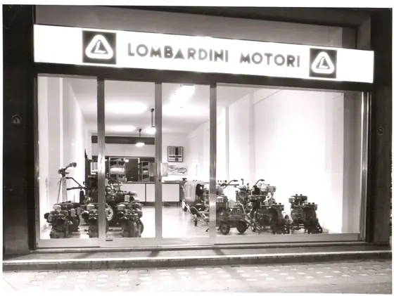 La vetrina «Lombardini Motori» di sera, in bianco e nero, con motozappe e motocoltivatori esposti