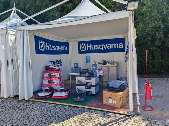 Il gazebo Husqvarna visto di fronte, con robot, trattorini e attrezzi