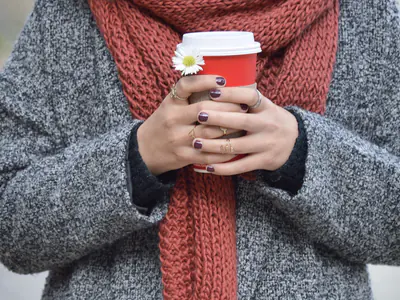 Mani che tengono un bicchiere di caffè da portare via