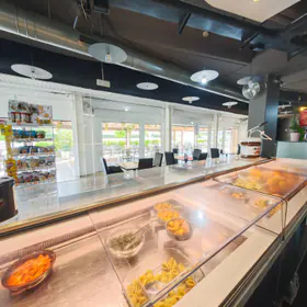 Il banco della tavola calda, con le vaschette in vetrina e la sala sullo sfondo