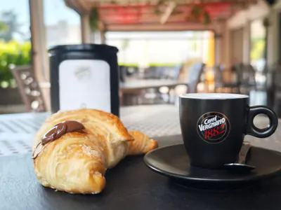 Cornetto e caffè in tazza Vergnano, su un vassoio di ardesia