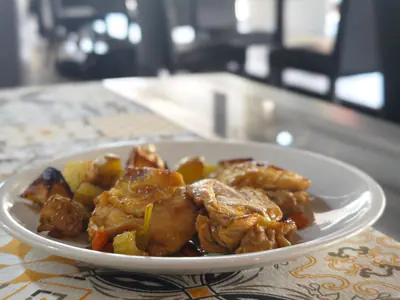 Pollo arrosto con patate e verdure, su un piatto bianco