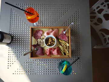 Il tagliere dell'aperitivo visto dall'alto, fra uno spritz e un cocktail blu