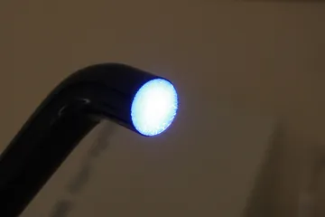 La punta accesa di una lampada fotopolimerizzatrice, con la sua luce blu