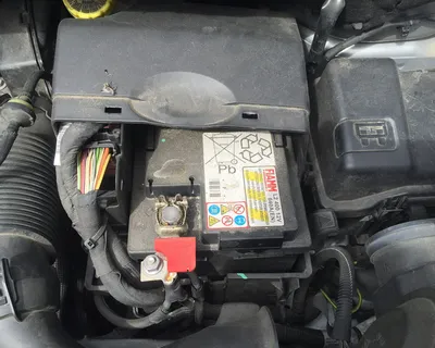 La batteria di un'auto al suo posto nel vano motore, con il cappuccio rosso sul polo positivo