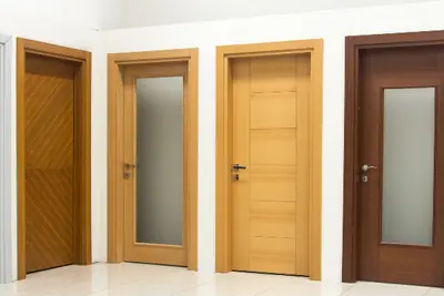 Una fila di porte interne in legno chiaro e scuro, alcune con il vetro satinato