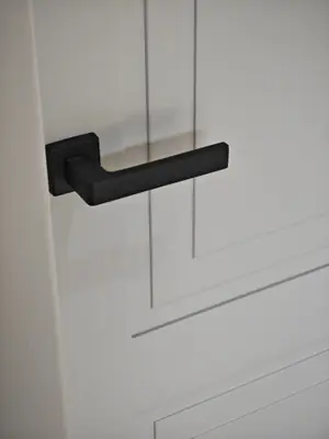 Una maniglia nera su una porta bianca, da vicino