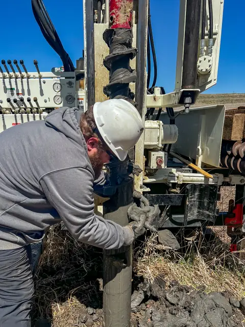 Un tecnico con il casco bianco guida la trivella che scende nel terreno