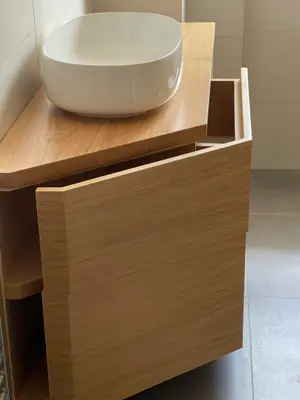 Mobile bagno in legno chiaro con il lavabo bianco d’appoggio
