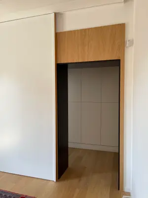 Ingresso della cabina armadio incorniciato in legno, con ante bianche