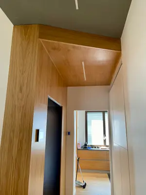 Corridoio con parete e soffitto rivestiti in legno e una porta nera a filo