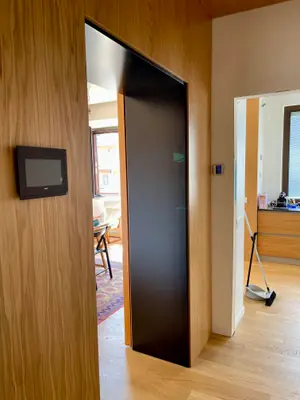 Parete rivestita in legno con un passaggio dal telaio nero verso la cucina