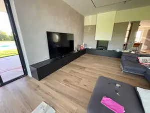 Soggiorno con il mobile TV basso e sospeso, scuro, lungo tutta la parete