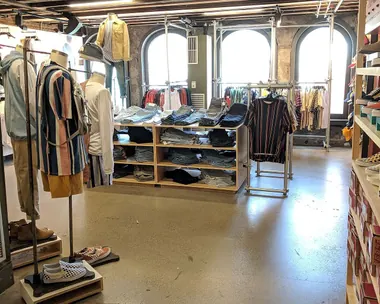 Negozio di abbigliamento con banchi e scaffali in legno chiaro