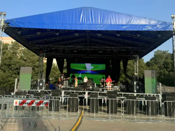 Palco con la copertura blu e lo schermo LED in una piazza, di giorno