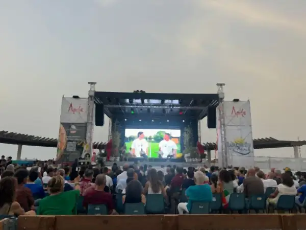 Un grande schermo LED su un palco all’aperto, con il pubblico seduto davanti