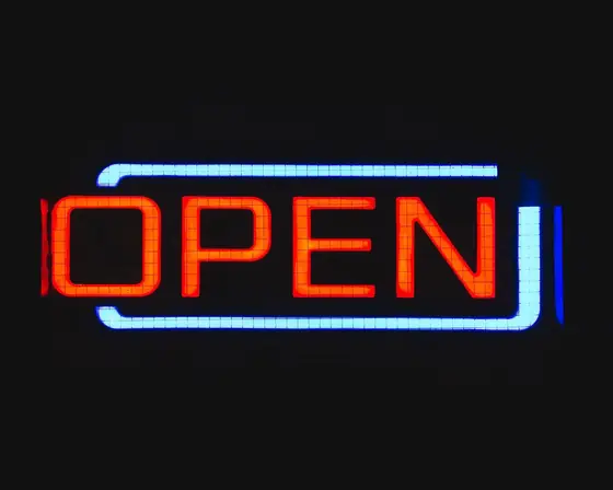 Un’insegna a LED «OPEN», rossa dentro una cornice azzurra, sul nero
