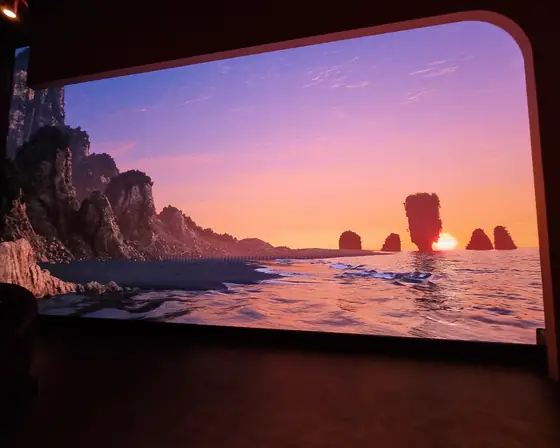 Una parete LED enorme che mostra un tramonto sul mare fra le scogliere