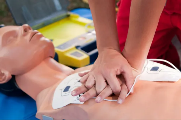 Massaggio cardiaco su un manichino con le piastre del defibrillatore già applicate