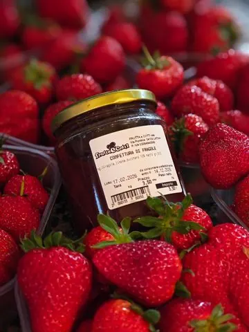 Fragole fresche e un barattolo di confettura di fragole con l’etichetta di Frutta e Cotti