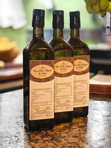 Tre bottiglie di olio extravergine d’oliva sul bancone del negozio