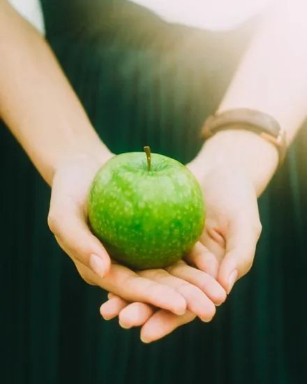 Due mani che tengono una mela verde