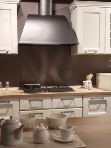 Cucina classica bianca con cappa a camino grigia e servizio da tè sul piano in legno