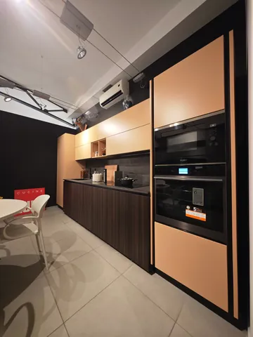 Cucina con basi scure a doghe e colonne color legno con forni a incasso
