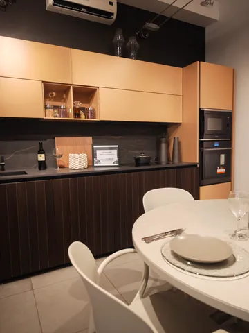 Cucina con pensili color legno chiaro, basi scure a doghe e tavolo rotondo apparecchiato