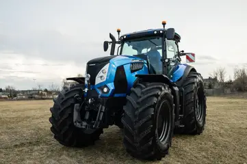 Un trattore azzurro in un campo, sotto un cielo nuvoloso