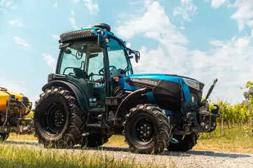 Un trattore azzurro specializzato su una strada di campagna